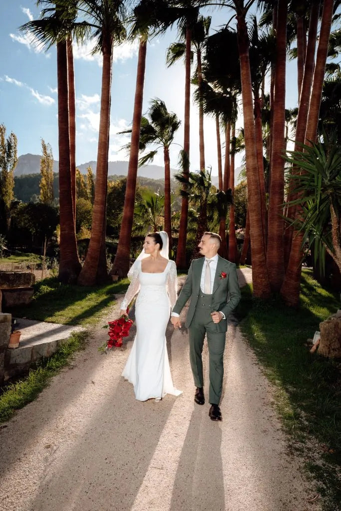 Brautpaar läuft Hand in Hand durch eine Palmenallee, Hochzeitsfoto im Stil der Editorial Wedding Presets
